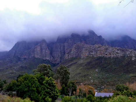 View of the rugged Langeberg mountains with dramatic peaks partially obscured by low hanging clouds green slopes and native vegetation in Montagu Western Cape South Africa.