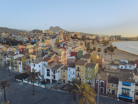 Aerial view of the iconic colorful houses along the Mediterranean coast with a sandy beach and palm trees in La Vila Joiosa Valencian Community Spain. Aerial view of the iconic colorful houses along the Mediterranean coast with a sandy beach and palm trees in La Vila Joiosa Valencian Community Spain.