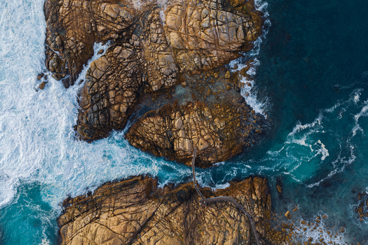 Aerial view of the wooden footbridge at Canal Rocks surrounded by rugged rock formations and turquoise ocean waves in Yallingup Western Australia Australia.