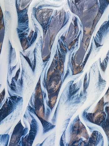 Aerial view of a braided river with glacial water flowing through dark volcanic sediment in Iceland. Aerial view of a braided river with glacial water flowing through dark volcanic sediment in Iceland.