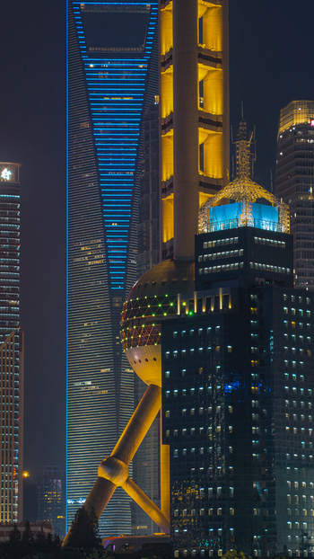 Aerial view of the illuminated Lujiazui skyline at night featuring the Oriental Pearl Tower and Shanghai Tower in the urban landscape of Shanghai Shanghai China.