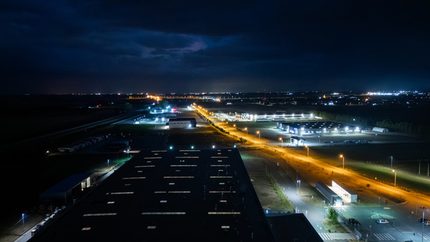 Aerial view of illuminated industrial buildings and warehouses at night with bright parking lot lights and surrounding roads in Sremska Mitrovica Vojvodina Serbia. Aerial view of illuminated industrial buildings and warehouses at night with bright parking lot lights and surrounding roads in Sremska Mitrovica Vojvodina Serbia.