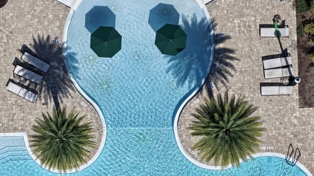 Aerial view of swimming pool with green umbrellas lounge chairs and palm trees at Windward Ranch Boulevard in St. Johns County Florida United States. Aerial view of swimming pool with green umbrellas lounge chairs and palm trees at Windward Ranch Boulevard in St. Johns County Florida United States.
