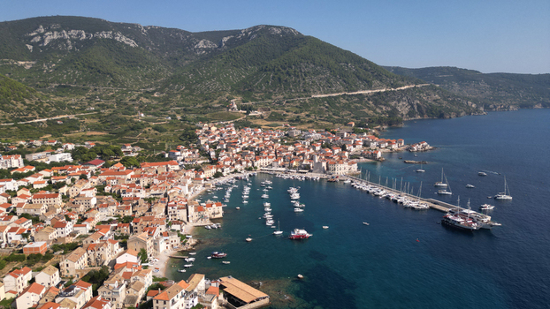 Aerial view of the coastal town of Komiza with its harbor full of boats and red roofed houses nestled against green mountains Komiza Split Dalmatia County Croatia.