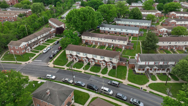 Aerial view of a residential neighborhood featuring rows of townhouses with green lawns mature trees and cars parked along the street in North York Pennsylvania United States. Aerial view of a residential neighborhood featuring rows of townhouses with green lawns mature trees and cars parked along the street in North York Pennsylvania United States.