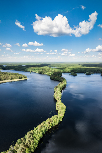 Aerial view of the narrow forested esker of Liesjarvi National Park surrounded by deep blue lake waters under a bright sunny sky in Tammela Finland. Aerial view of the narrow forested esker of Liesjarvi National Park surrounded by deep blue lake waters under a bright sunny sky in Tammela Finland.