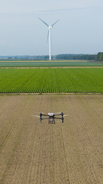 Aerial view of a drone flying over a cultivated agricultural field with a wind turbine in the background in Zeewolde Flevoland Netherlands. Aerial view of a drone flying over a cultivated agricultural field with a wind turbine in the background in Zeewolde Flevoland Netherlands.