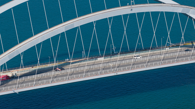 Aerial view of the Cross Bay Link bridge with cars driving across the modern white arch structure over the deep blue sea in Hong Kong Hong Kong.