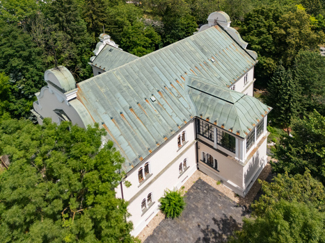 Aerial view of Tihanyi Mansion a historic building with a distinctive green metal roof surrounded by lush green trees in Banska Bystrica Banskobystricky kraj Slovakia. Aerial view of Tihanyi Mansion a historic building with a distinctive green metal roof surrounded by lush green trees in Banska Bystrica Banskobystricky kraj Slovakia.