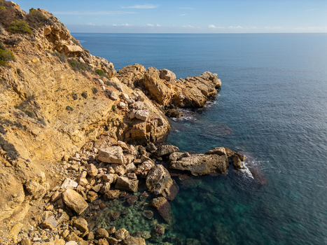 Aerial view of the rugged cliffs and turquoise waters of Cala Llebeig in El Poble Nou de Benitatxell Valencian Community Spain.