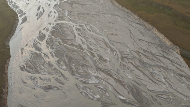 Aerial view of the braided channels of the Enilchek River with sediment laden water flowing through the grassy landscape of Enilchek Issyk Kul Region Kyrgyzstan. Aerial view of the braided channels of the Enilchek River with sediment laden water flowing through the grassy landscape of Enilchek Issyk Kul Region Kyrgyzstan.