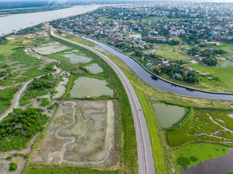 Aerial view of Kalurghat New River view Road stretching alongside the Karnaphuli River with lush green wetlands and the urban skyline of Chattogram Chittagong Division Bangladesh.