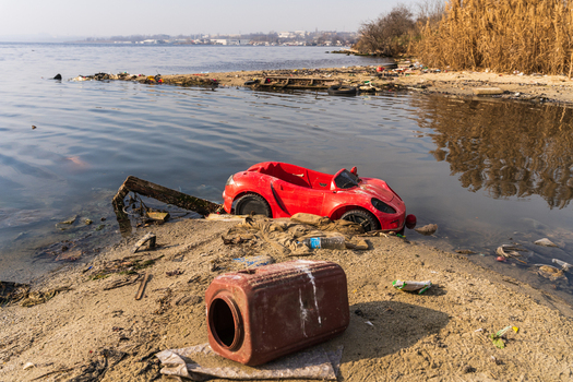 View of a red toy car abandoned on the sandy shore of Lake Varna with plastic debris and a container in the foreground Varna Bulgaria. View of a red toy car abandoned on the sandy shore of Lake Varna with plastic debris and a container in the foreground Varna Bulgaria.