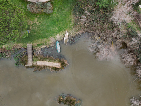 Aerial view of wooden boats moored near a small pier at the edge of Scamandre Regional Nature Reserve with murky water and bare trees in Arles Provence Alpes Cote d Azur France. Aerial view of wooden boats moored near a small pier at the edge of Scamandre Regional Nature Reserve with murky water and bare trees in Arles Provence Alpes Cote d Azur France.