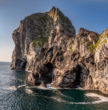 Aerial view of the rugged sea cliffs at Glenlough Bay with dark rock formations and crashing waves in Ardara County Donegal Ireland.