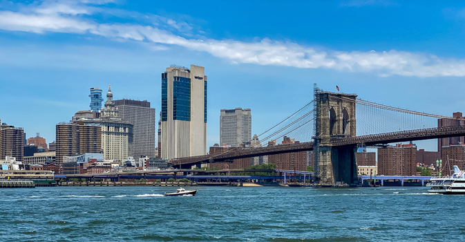 View of the Brooklyn Bridge spanning the East River with the Manhattan skyline in the background under a clear blue sky in New York New York United States. View of the Brooklyn Bridge spanning the East River with the Manhattan skyline in the background under a clear blue sky in New York New York United States.