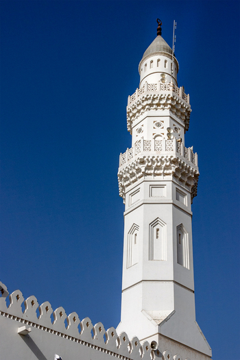 View of the ornate white minaret of Masjid Quba standing against a clear blue sky in Madinah Al Madinah Province Saudi Arabia.