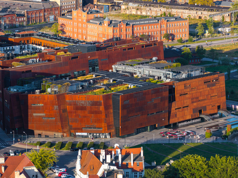 Aerial view of the European Solidarity Centre with its distinctive rust colored facade and green roof situated in the historic shipyard area of Gdansk Pomeranian Voivodeship Poland. Aerial view of the European Solidarity Centre with its distinctive rust colored facade and green roof situated in the historic shipyard area of Gdansk Pomeranian Voivodeship Poland.