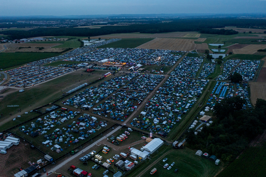 Aerial view of the Open Beatz Festival campsite with numerous tents and vehicles spread across green fields at dusk in Herzogenaurach Bayern Germany. Aerial view of the Open Beatz Festival campsite with numerous tents and vehicles spread across green fields at dusk in Herzogenaurach Bayern Germany.