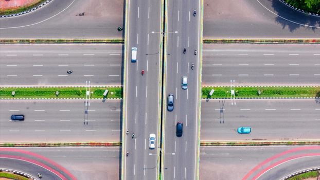 Aerial view of a highway interchange with vehicles and motorcycles driving on multi lane roads separated by green median strips in Jakarta Indonesia. Aerial view of a highway interchange with vehicles and motorcycles driving on multi lane roads separated by green median strips in Jakarta Indonesia.