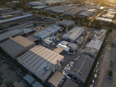 Melbourne VIC Australia 22 September 2026 Aerial view of industrial factories in Kilsyth with metal rooftops storage tanks and paved areas under warm afternoon light. Melbourne VIC Australia 22 September 2026 Aerial view of industrial factories in Kilsyth with metal rooftops storage tanks and paved areas under warm afternoon light.