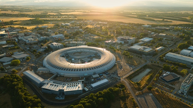Aerial view of Diamond Light Source a circular synchrotron facility surrounded by greenery under golden hour light in Didcot United Kingdom.