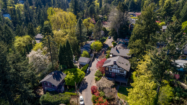 Aerial view of residential houses along Southwest Imperial Drive surrounded by lush green trees and spring blossoms in a quiet neighborhood Portland Oregon United States. Aerial view of residential houses along Southwest Imperial Drive surrounded by lush green trees and spring blossoms in a quiet neighborhood Portland Oregon United States.