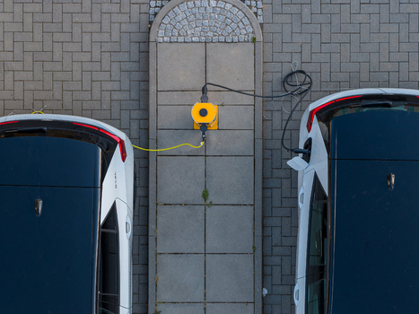 Aerial view of two electric cars plugged into the yellow ENTEGA Charging Station on a paved parking lot in Darmstadt Hessen Germany. Aerial view of two electric cars plugged into the yellow ENTEGA Charging Station on a paved parking lot in Darmstadt Hessen Germany.