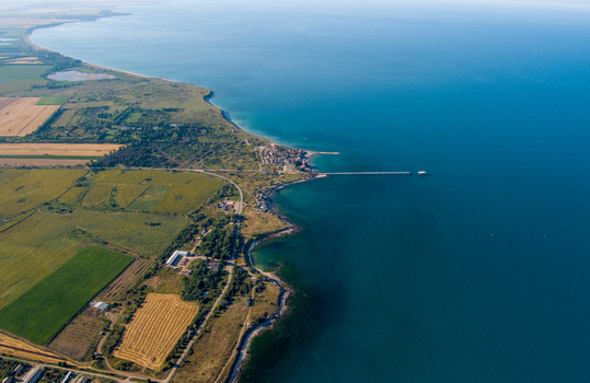 Aerial view of the coastline at Saints Constantine and Helena featuring a long pier extending into the sea surrounded by fields in Saints Constantine and Helena Varna Bulgaria.