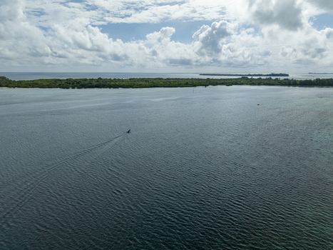 Aerial view of a boat cutting through the tranquil deep blue waters towards the distant verdant islands under a sky brushed with clouds Karimunjawa Jawa Tengah Indonesia. Aerial view of a boat cutting through the tranquil deep blue waters towards the distant verdant islands under a sky brushed with clouds Karimunjawa Jawa Tengah Indonesia.