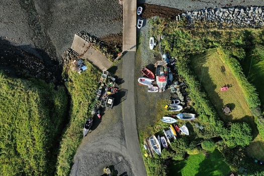 Aerial view of a boat ramp with small boats and trailers parked on the grassy shore in Stein Scotland United Kingdom. Aerial view of a boat ramp with small boats and trailers parked on the grassy shore in Stein Scotland United Kingdom.