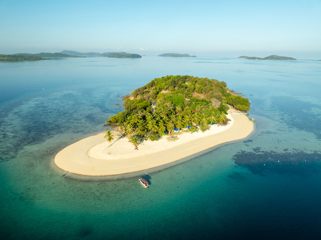 Aerial view of Pass Island featuring a white sand beach lush palm trees and turquoise waters in the surrounding sea Coron Philippines. Aerial view of Pass Island featuring a white sand beach lush palm trees and turquoise waters in the surrounding sea Coron Philippines.