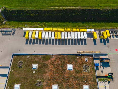 Aerial view of Logistikzentrum Allhaming featuring a green roof rows of yellow and white shipping containers and an asphalt yard in Allhaming Oberosterreich Austria. Aerial view of Logistikzentrum Allhaming featuring a green roof rows of yellow and white shipping containers and an asphalt yard in Allhaming Oberosterreich Austria.
