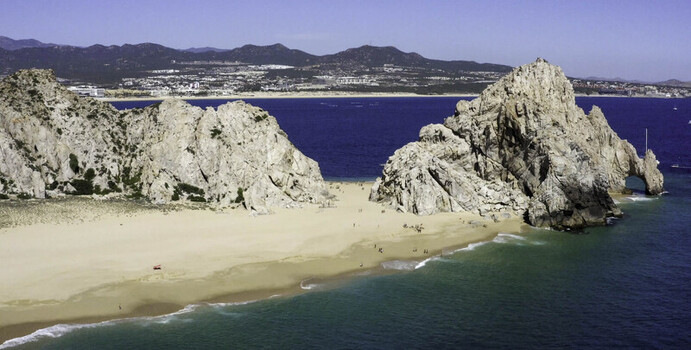 Aerial view of El Arco rock formation at Land s End featuring golden sandy beaches turquoise waters and rugged coastal cliffs in Cabo San Lucas Baja California Sur Mexico.