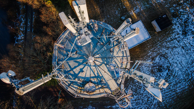 Valmiera Latvia 11 November 2025 Aerial view of a telecommunications tower with antennas and satellite dishes in a rural area.