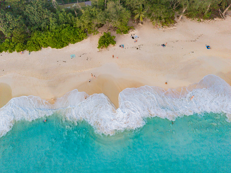 Aerial view of turquoise waves crashing onto the sandy beach fringed by lush green trees contrasting textures under the sun Quatre Bornes Mahe Island Seychelles. Aerial view of turquoise waves crashing onto the sandy beach fringed by lush green trees contrasting textures under the sun Quatre Bornes Mahe Island Seychelles.