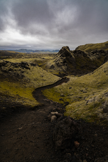View of a winding path cuts through a mossy volcanic landscape under a brooding sky highlighting the raw beauty Skaftárhreppur Iceland. View of a winding path cuts through a mossy volcanic landscape under a brooding sky highlighting the raw beauty Skaftárhreppur Iceland.