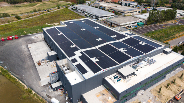 Aerial view of a modern logistics warehouse for fresh fruit and vegetable distribution featuring rooftop solar panels ventilation units and cooling systems in Melegnano Lombardy Italy.