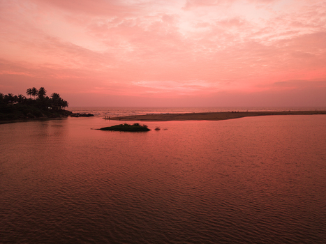 Aerial view of a tranquil river mouth meeting the ocean under a vibrant pink sunset sky with palm trees lining the shore Galle Southern Province Sri Lanka. Aerial view of a tranquil river mouth meeting the ocean under a vibrant pink sunset sky with palm trees lining the shore Galle Southern Province Sri Lanka.