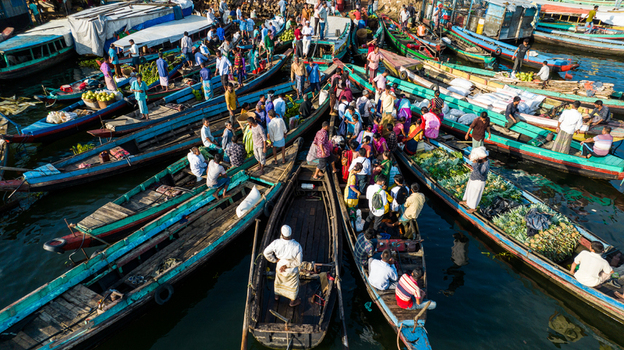Rangamati Chittagong Division Bangladesh 19 October 2022 Aerial view of a bustling floating market with wooden boats filled with produce and people navigating the waterway.
