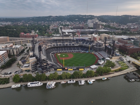 Pittsburgh Pennsylvania United States 26 July 2026 Aerial view of PNC Park stadium on the Allegheny River with boats at the waterfront urban buildings and cloudy sky.