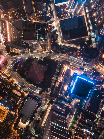 Aerial view of the illuminated cityscape at night featuring skyscrapers glowing office buildings and winding roads with traffic lights in Jakarta Indonesia.