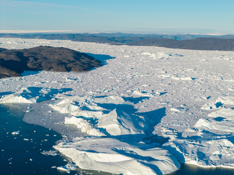 Aerial view of Ilulissat glacier with massive icebergs floating in the dark blue water along the rocky coastline of Greenland. Aerial view of Ilulissat glacier with massive icebergs floating in the dark blue water along the rocky coastline of Greenland.