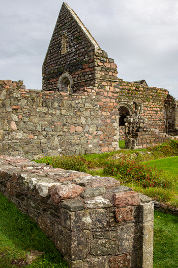 View of Iona Nunnery ruins with ancient stone walls and arched windows under a cloudy sky in Baile Mor Scotland United Kingdom. View of Iona Nunnery ruins with ancient stone walls and arched windows under a cloudy sky in Baile Mor Scotland United Kingdom.