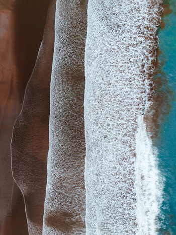 Aerial view of waves crashing onto the dark sand beach in Costa Rica.