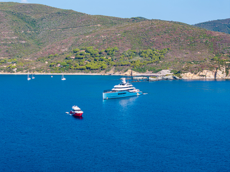 Aerial view of the luxury yacht Netto II anchored in the blue waters of Lacona Bay on Elba island surrounded by green hills and coastal landscape in Lacona Tuscany Italy.
