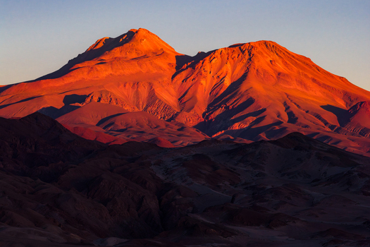 Aerial view of majestic mountain peaks glowing in the warm light of sunset over the arid desert landscape Toconao Antofagasta Chile. Aerial view of majestic mountain peaks glowing in the warm light of sunset over the arid desert landscape Toconao Antofagasta Chile.