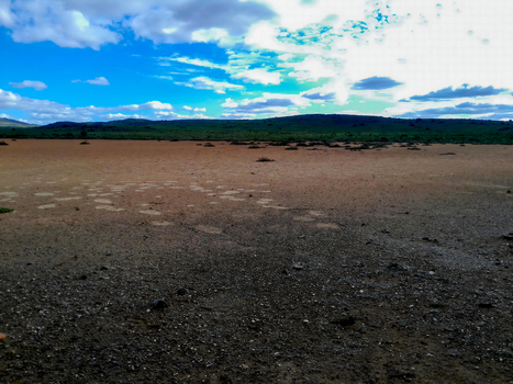 View of the semi arid plains and rugged hills of Anysberg Nature Reserve under a bright blue sky with scattered clouds in Anysberg Western Cape South Africa. View of the semi arid plains and rugged hills of Anysberg Nature Reserve under a bright blue sky with scattered clouds in Anysberg Western Cape South Africa.