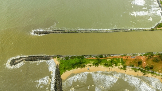 Aerial view of Malpe Fishing Harbour with stone breakwaters extending into the Arabian Sea sandy coastline and calm water channel in Udupi Karnataka India. Aerial view of Malpe Fishing Harbour with stone breakwaters extending into the Arabian Sea sandy coastline and calm water channel in Udupi Karnataka India.