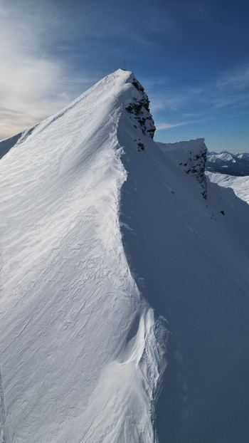 Aerial view of the sharp snow covered ridge of Aiguille Croche mountain peak under a clear blue sky in the French Alps Les Contamines Montjoie Auvergne Rhone Alpes France. Aerial view of the sharp snow covered ridge of Aiguille Croche mountain peak under a clear blue sky in the French Alps Les Contamines Montjoie Auvergne Rhone Alpes France.